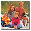family of four sitting on a blanket with a dog